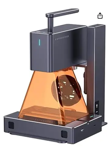 A compact laser engraver machine sitting on a workspace, used for creating permanent weather-proof QR code markers for roadside memorials.